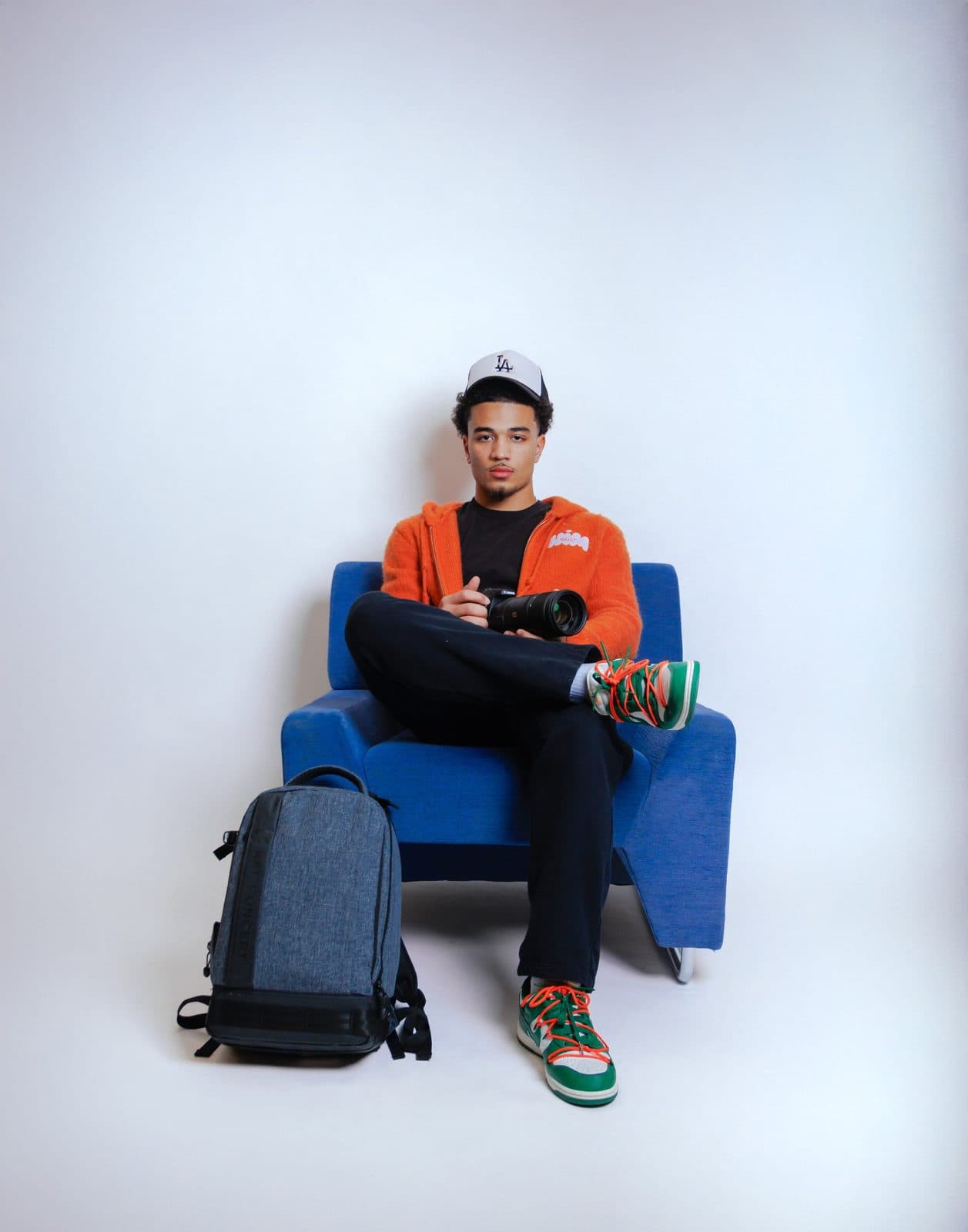 Jaedon Mast in a blue armchair with his Canon camera